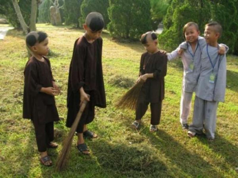 Chú tiểu cầm chổi quét lá trong chùa